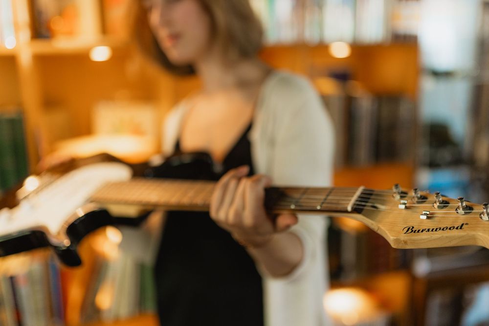 A musician plays an acoustic guitar in a warmly lit studio space during a recording session.