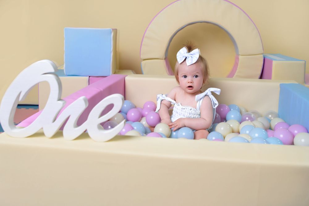 First birthday photo backdrop with pastel balloons, blocks, and 'one' text decoration.