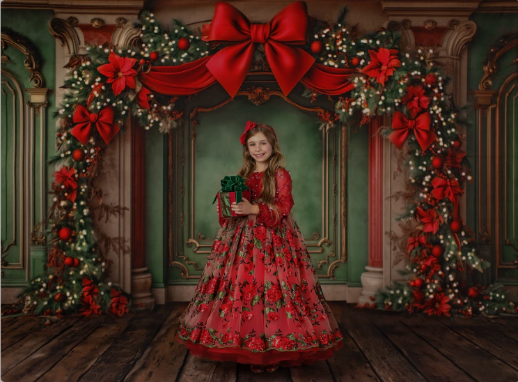 Elegant red ball gown with floral decorations photographed in an ornate room with Christmas decorations and bow accents.