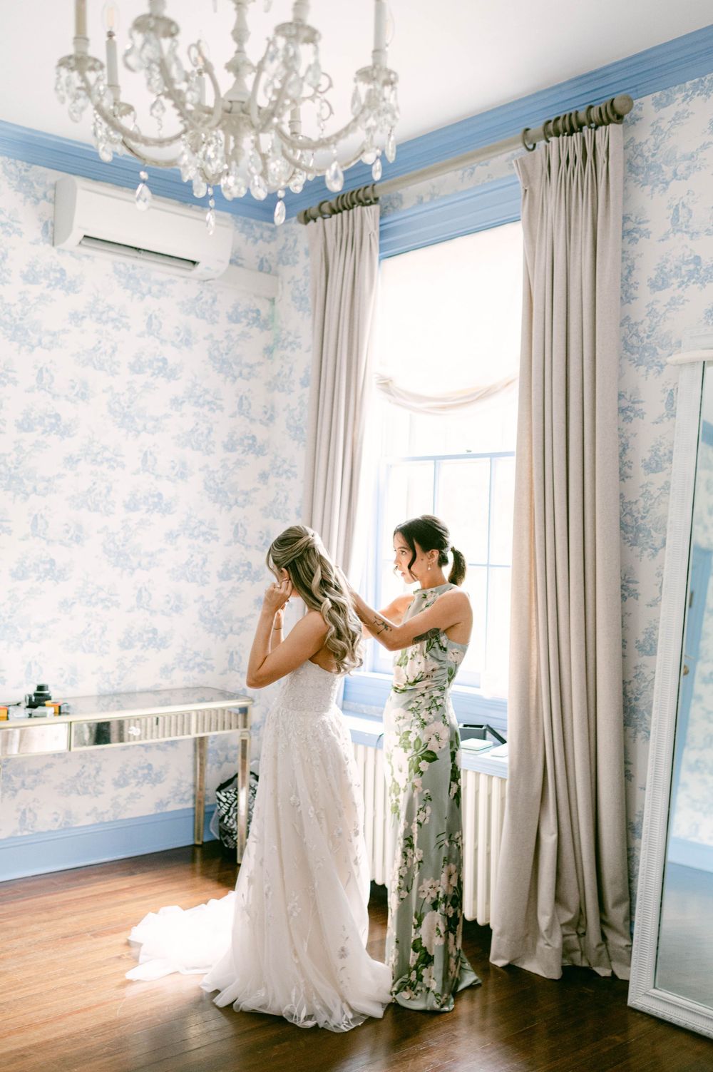 A beautiful Rust Manor House wedding preparation scene in an elegant blue and white room with a chandelier and flowing curtains.