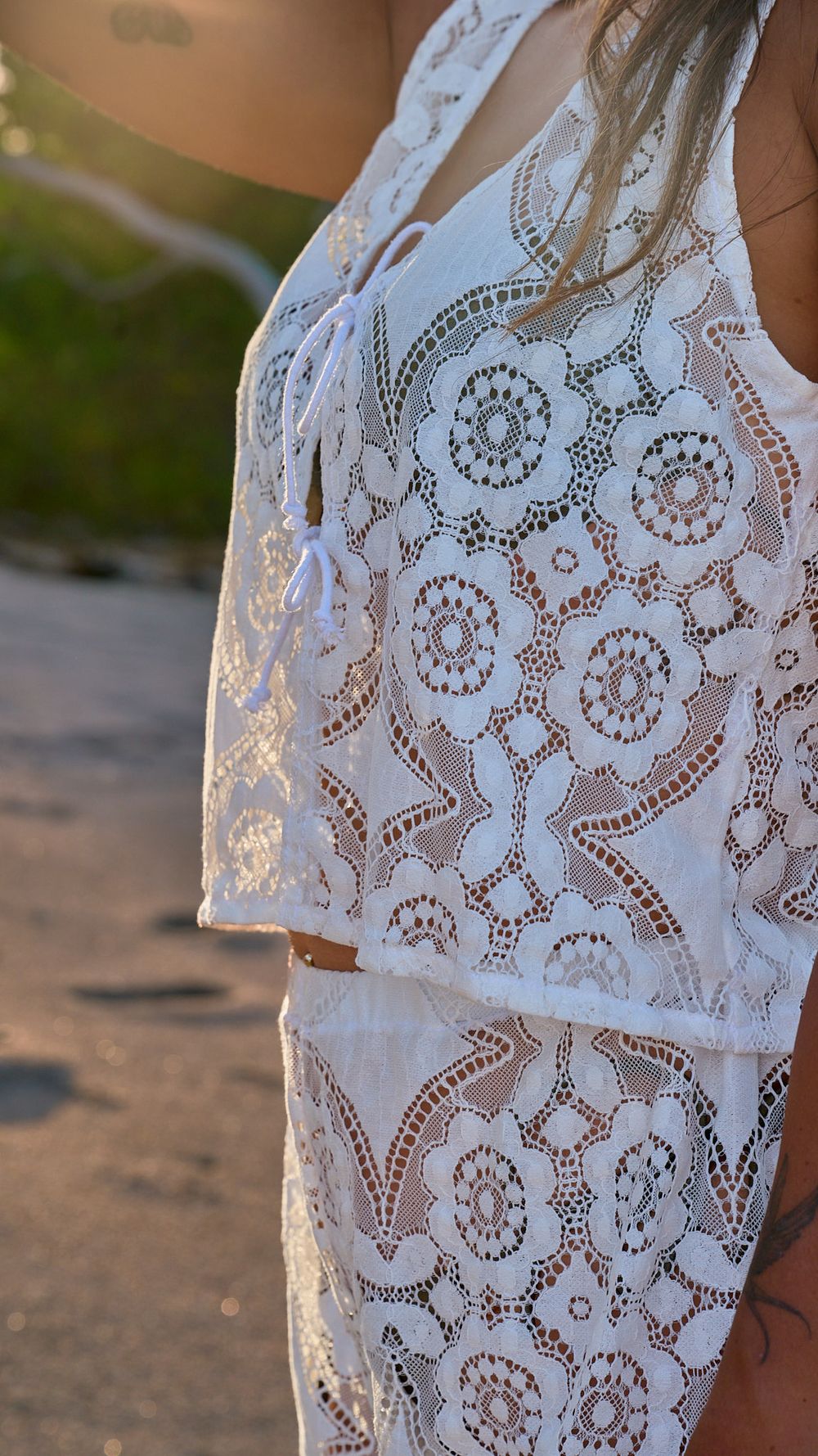 Detailed close-up of white lace pattern on a beach coverup with intricate floral and geometric designs.