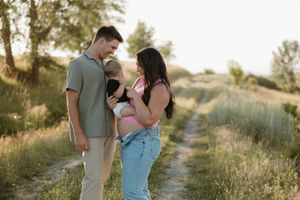 A family enjoying a tender outdoor moment together on a sunlit nature path in the countryside.