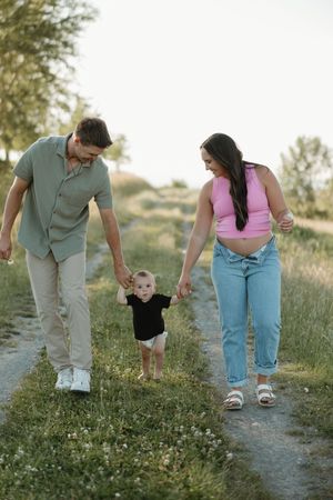 A family walks together along a dirt path through a wildflower meadow on a sunny summer day.
