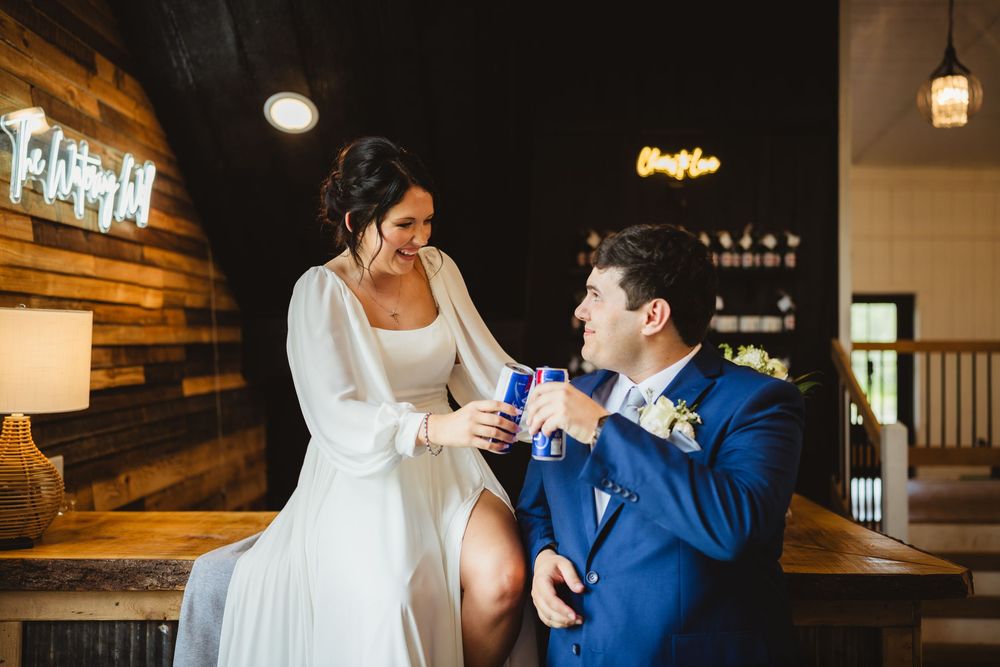 A couple in wedding attire share an intimate moment while illuminated by warm lighting in an elegant indoor setting.