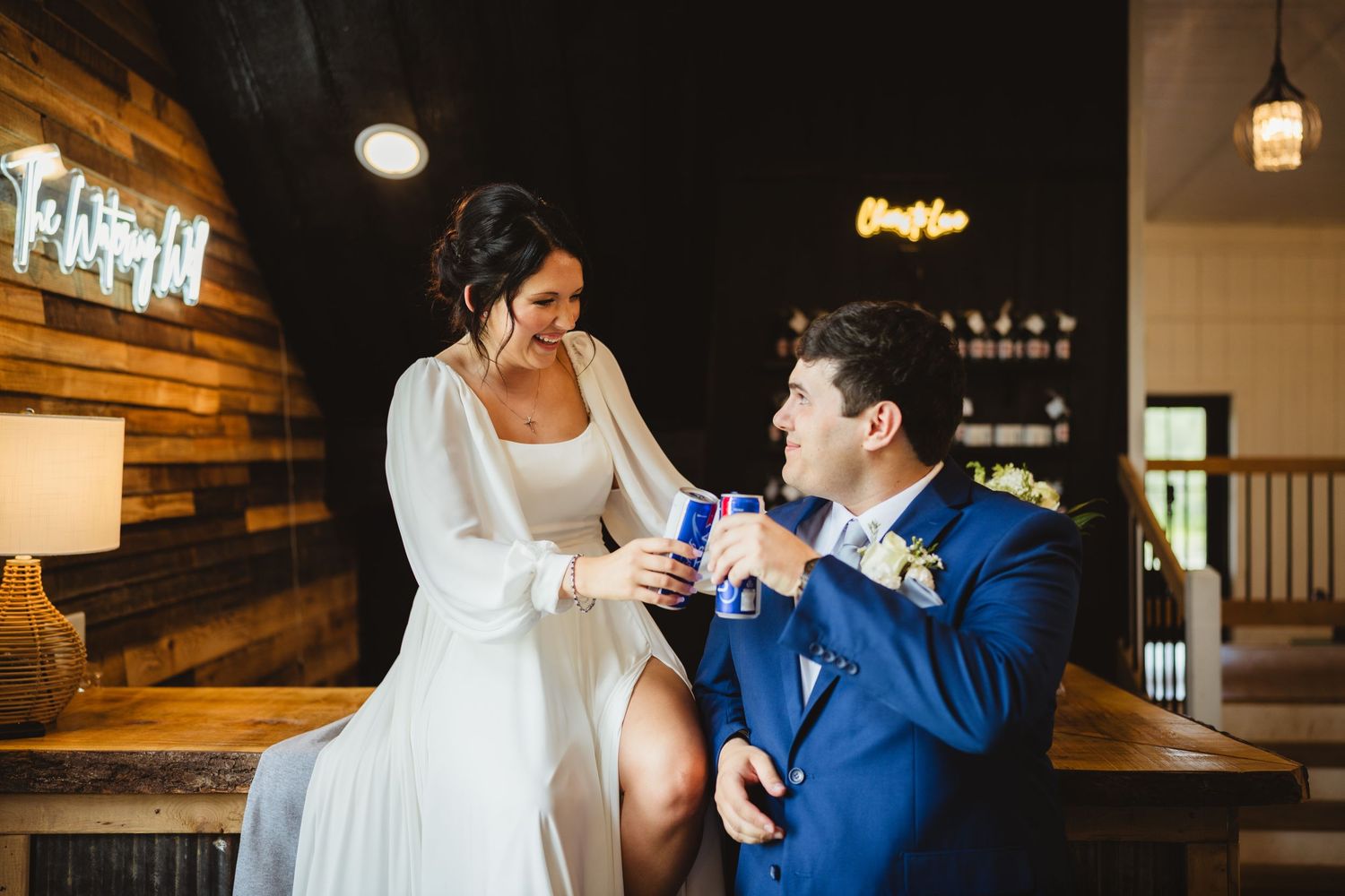 A couple in wedding attire share an intimate moment while illuminated by warm lighting in an elegant indoor setting.