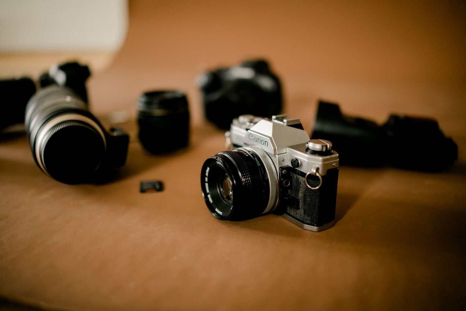 Vintage film camera with multiple lenses and accessories arranged on a brown surface.