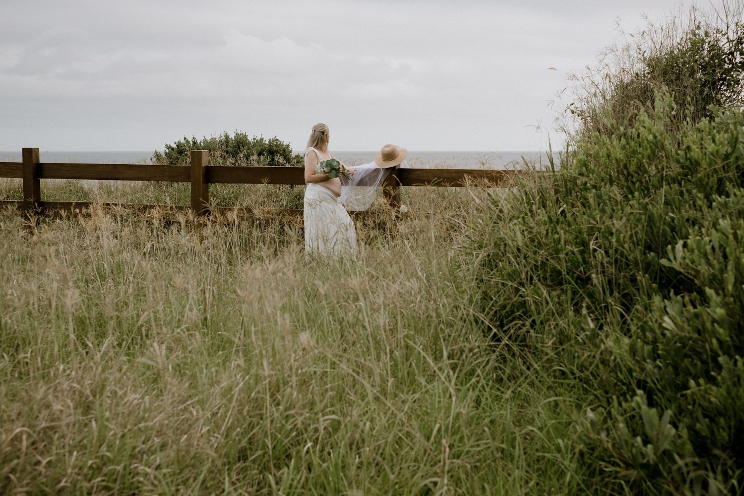 A rustic wooden fence stretches across a grassy meadow at golden hour.