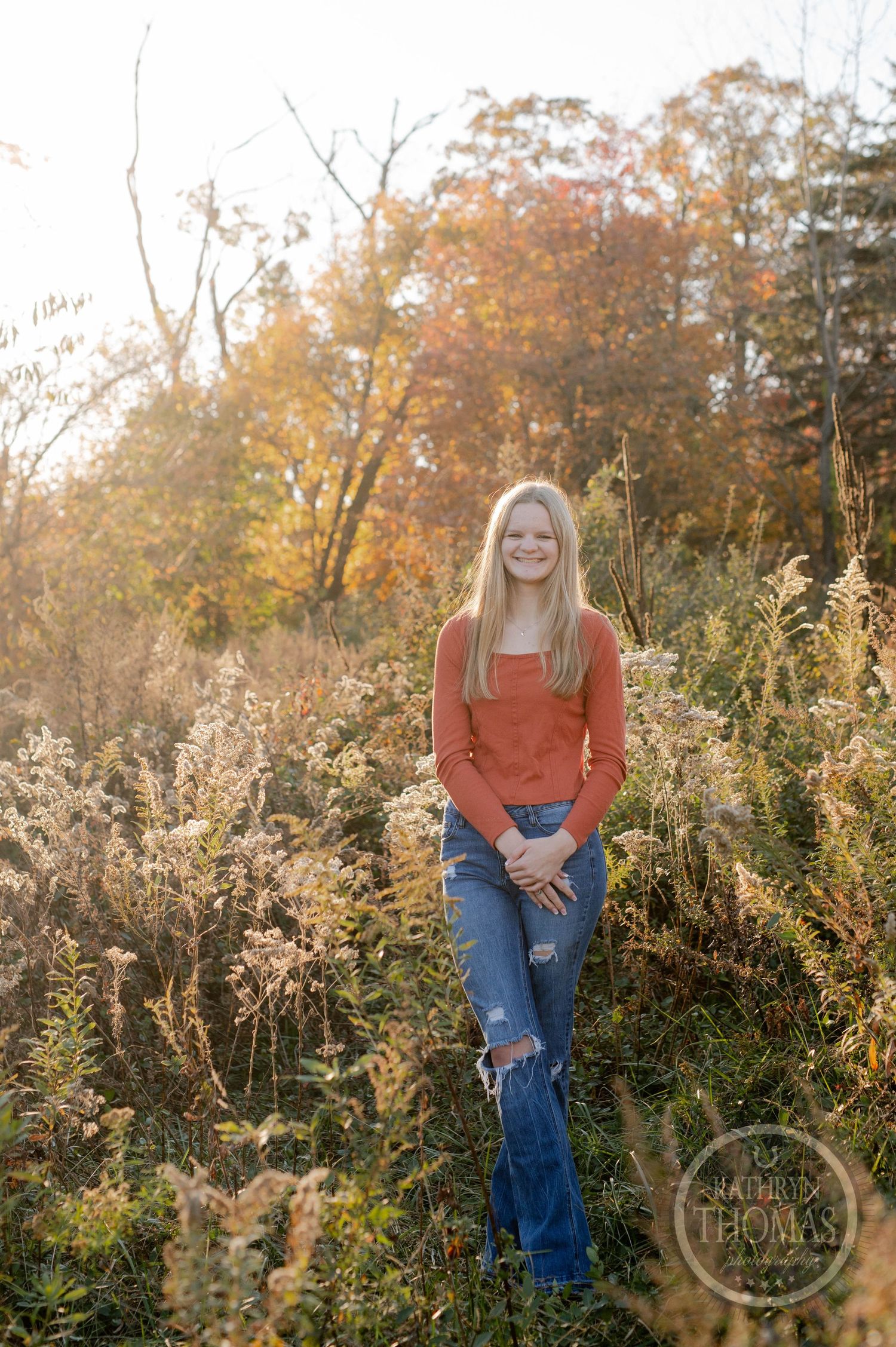 Natural outdoor portrait among tall grasses with autumn colors and late afternoon light.