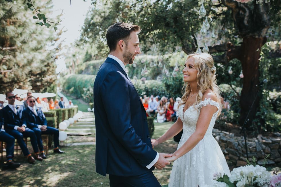 Beautiful outdoor wedding ceremony in a garden setting with couple holding hands during their vows.