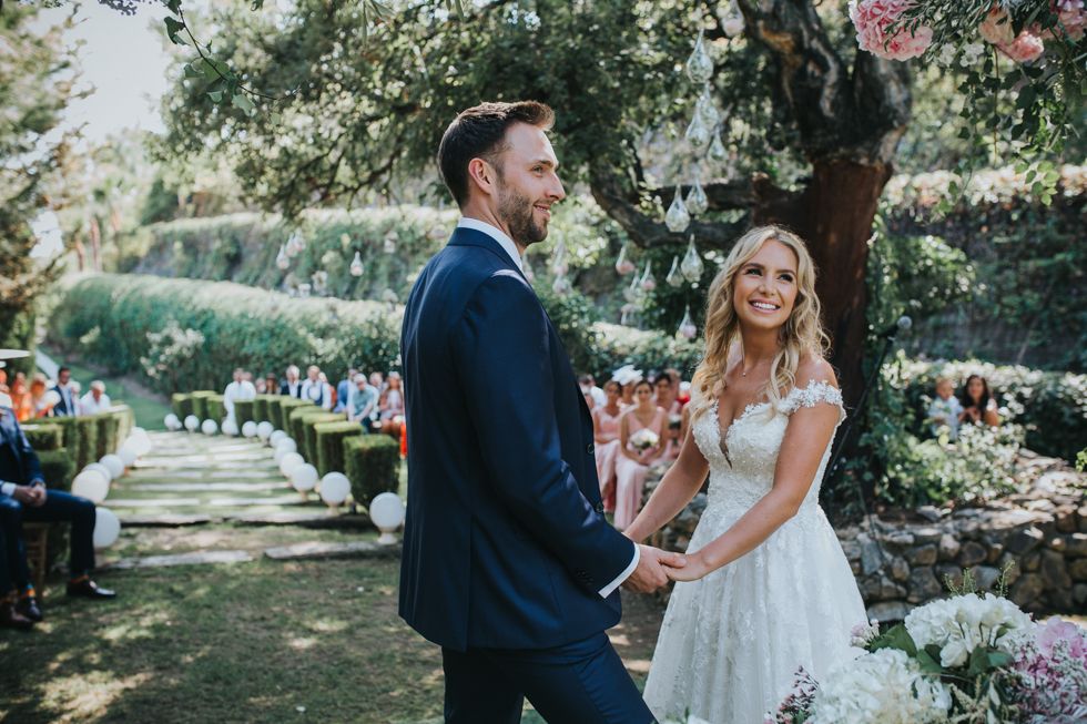 A newlywed couple shares a candid moment together during their garden wedding ceremony surrounded by flowers and greenery.