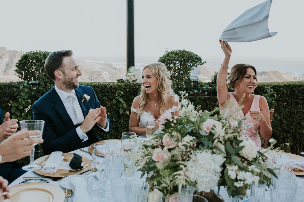 Joyful wedding celebration at an outdoor reception with elegant table settings and white floral centerpieces.