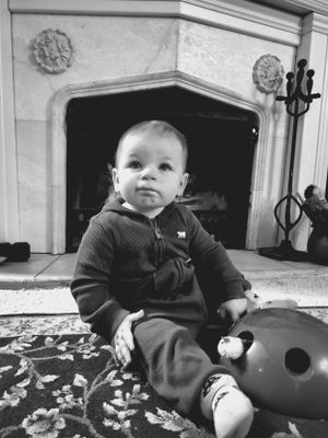 Baby sitting on stone steps wearing dark clothing and exploring surroundings.