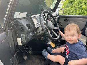 A child explores the interior of a parked vehicle.