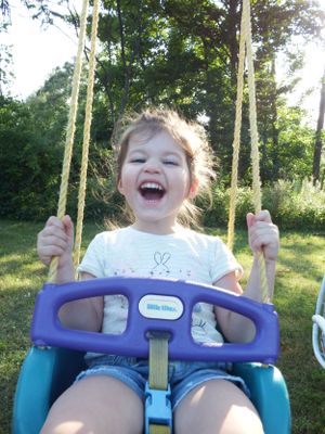Joyful moment captured on a backyard swing with sunlight filtering through trees.