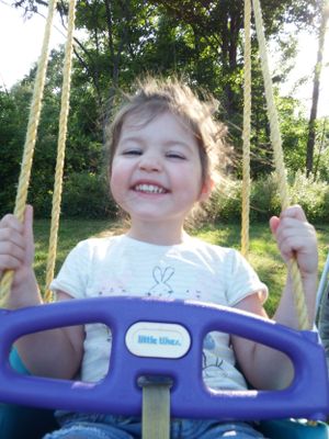 Close-up view of someone swinging on a purple and blue playground swing.