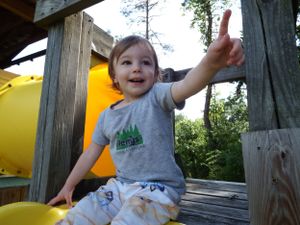 Outdoor playground scene with yellow equipment and wooden frame structure.
