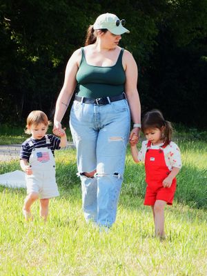 People walking through a sunny meadow wearing casual summer clothing.