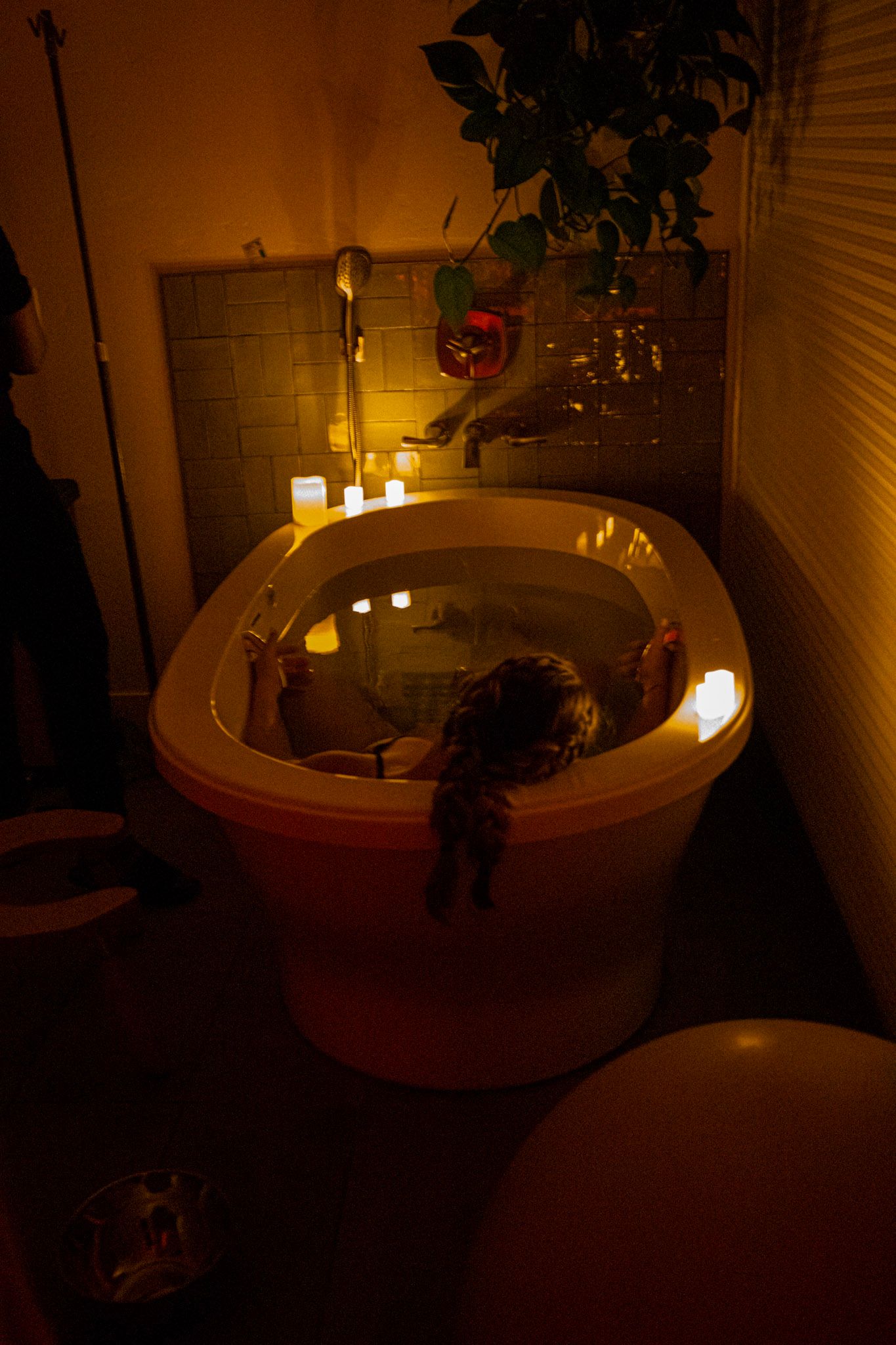 A bathroom setting with lit candles around a bathtub creating a warm, intimate atmosphere while a mother rests in a tub during labor.