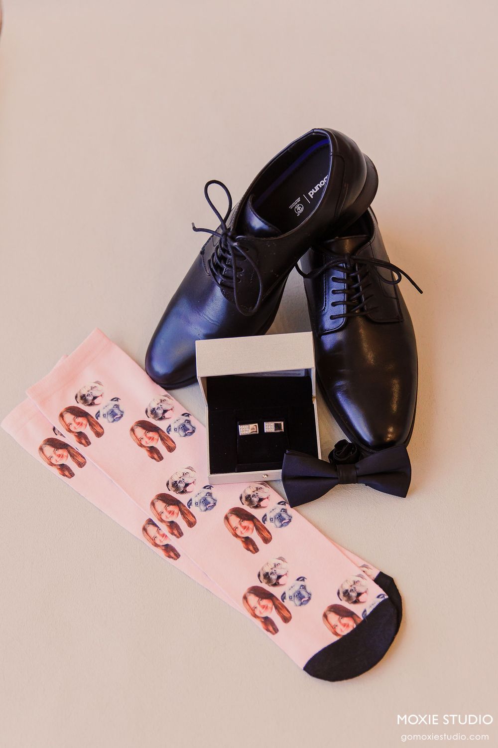 A sequence showing black leather dress shoes and pink greeting cards arranged in different compositions on a beige surface.