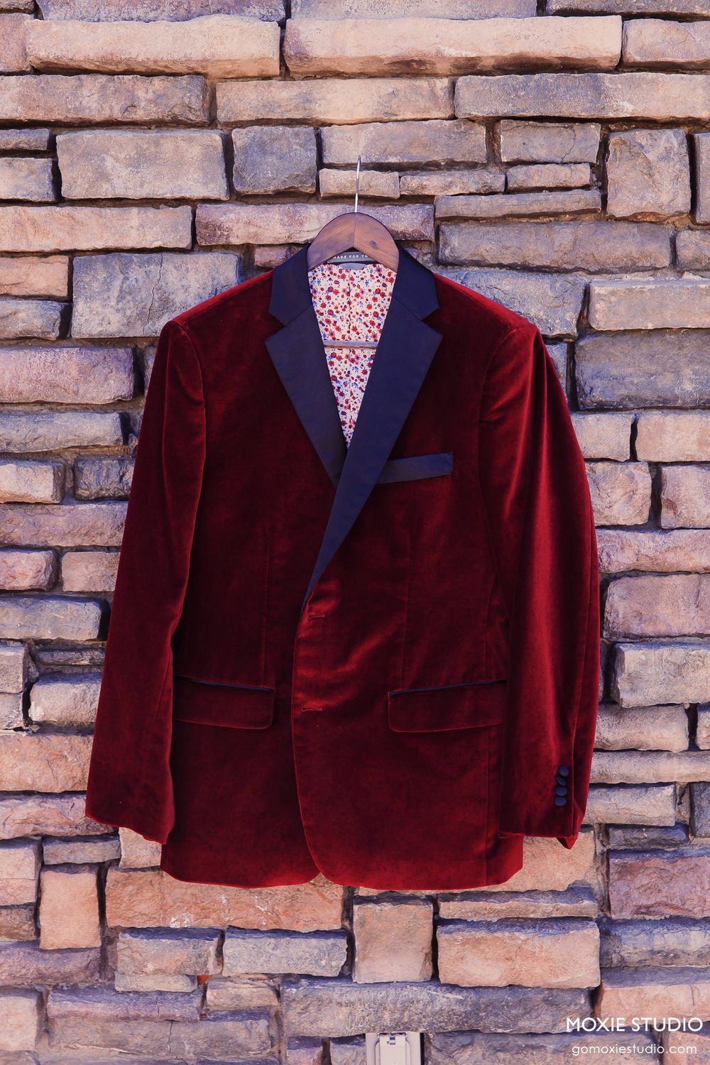 A sequence of photos showing a burgundy velvet tuxedo jacket with black lapels against a stone brick wall background.