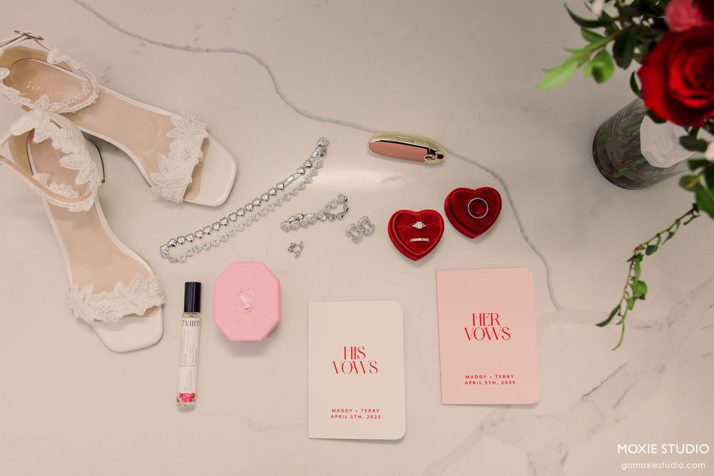 Pink and red beauty products arranged in a flat lay composition with roses and delicate accessories on a light background.