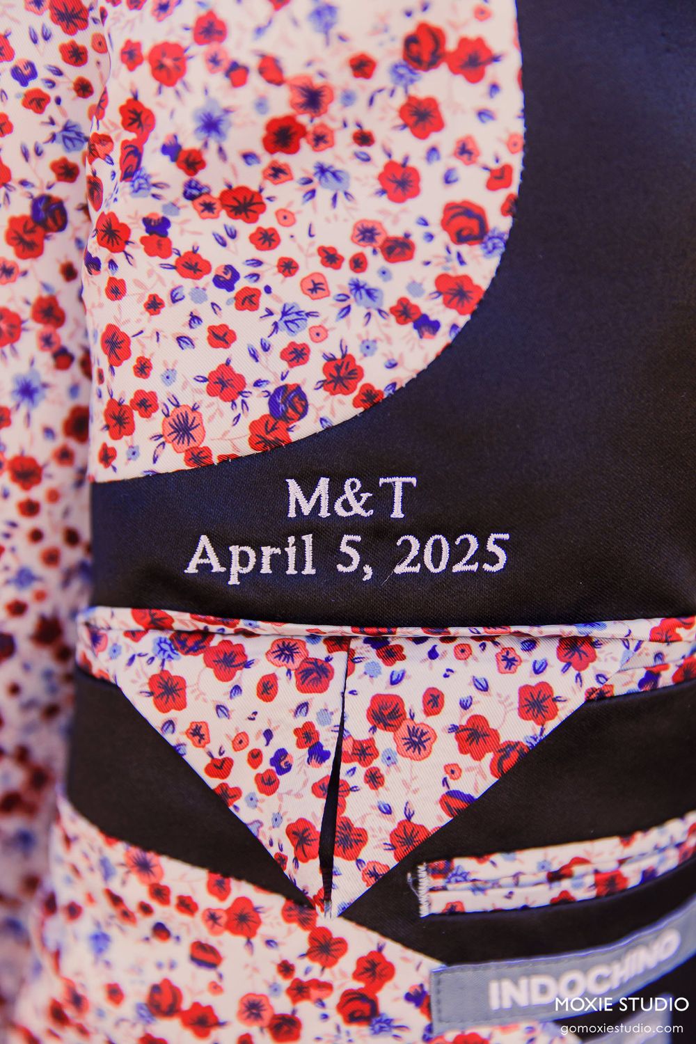Floral patterned fabric with red and blue flowers displays wedding date 'M&T April 5, 2025' on black background.