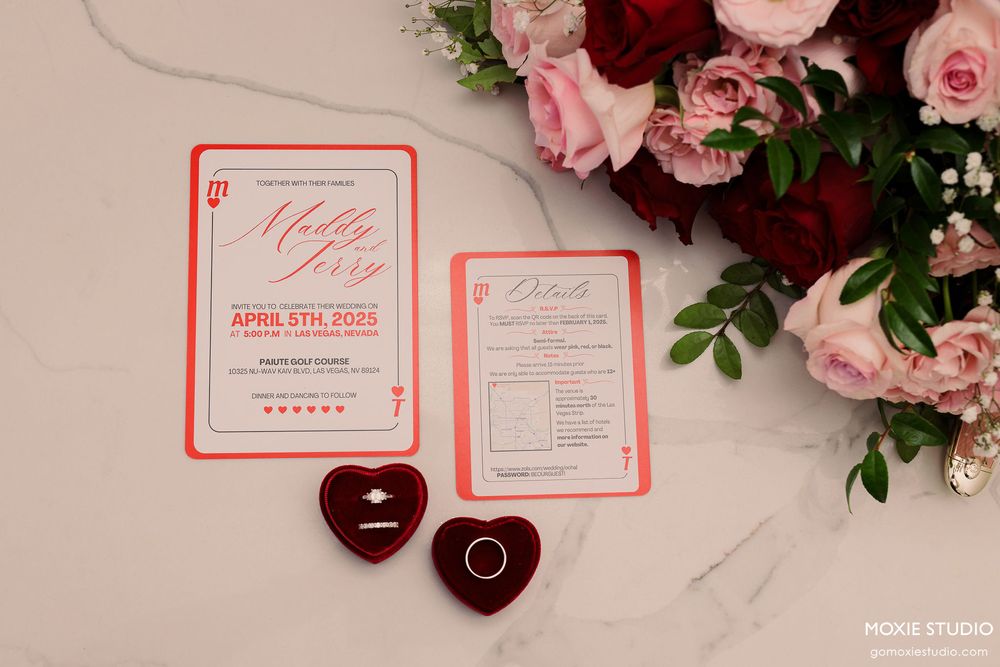 Wedding stationery and floral details in pink and burgundy tones arranged on marble surface.