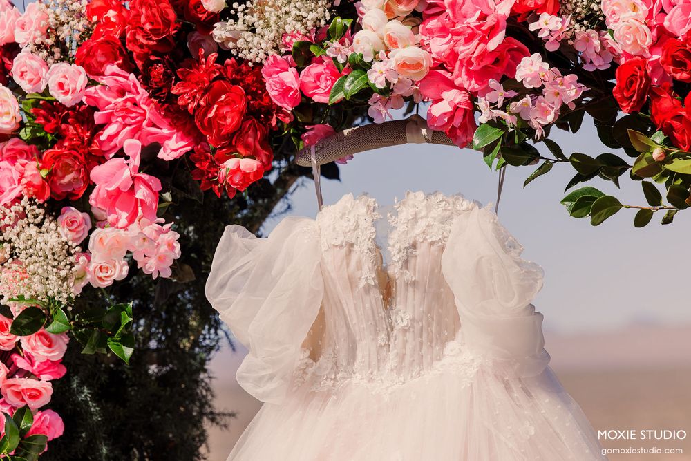 Close-up view of pink and red floral wedding arch arrangements with white tulle accents.