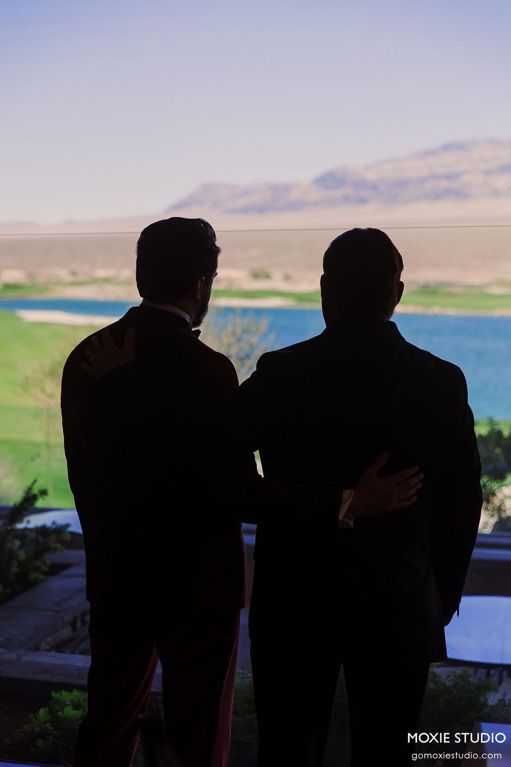 Silhouettes of people against a scenic lake and mountain landscape at sunset.