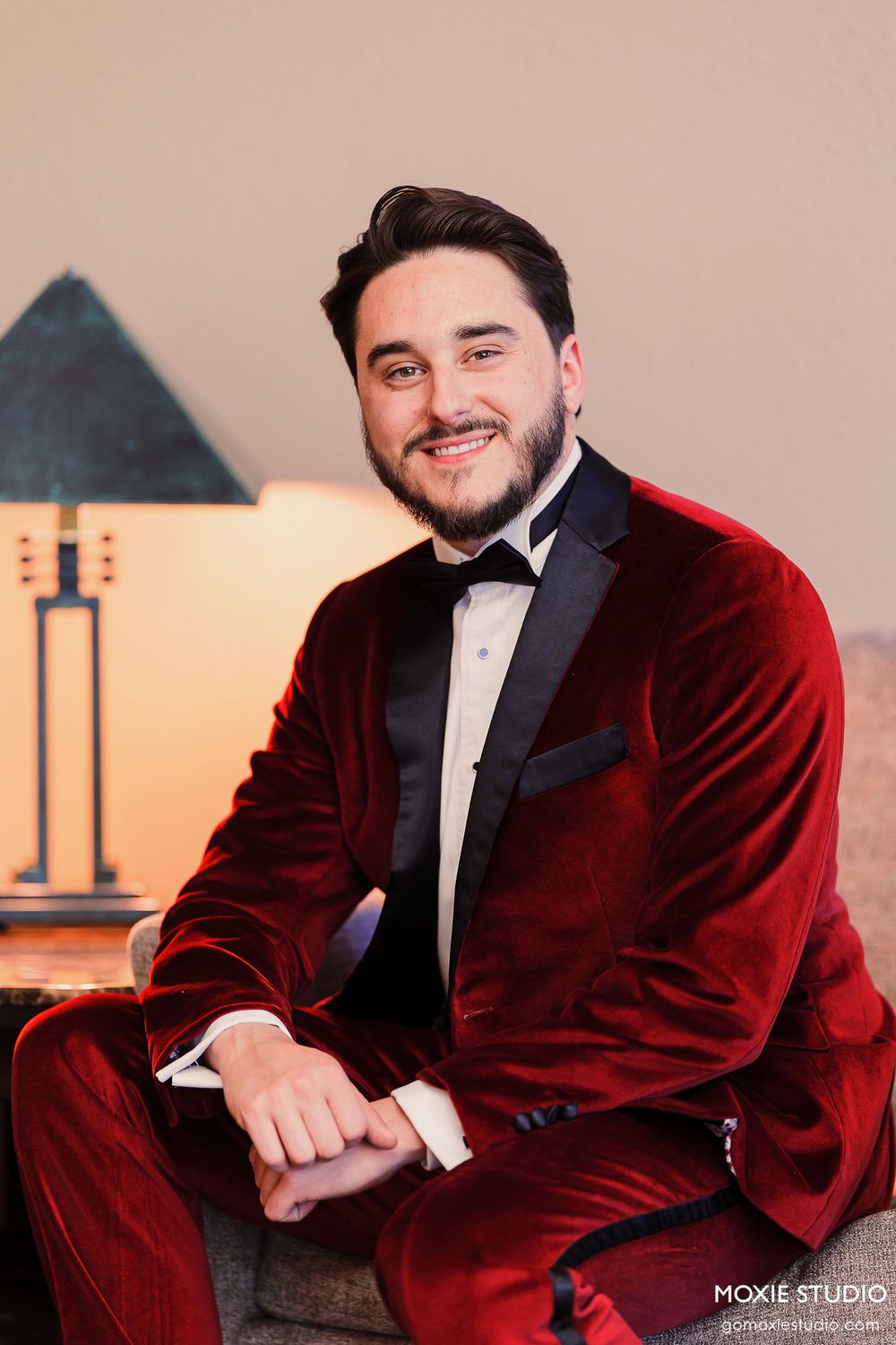 Professional portrait series featuring someone in a luxurious burgundy velvet tuxedo jacket against a warm-toned backdrop.