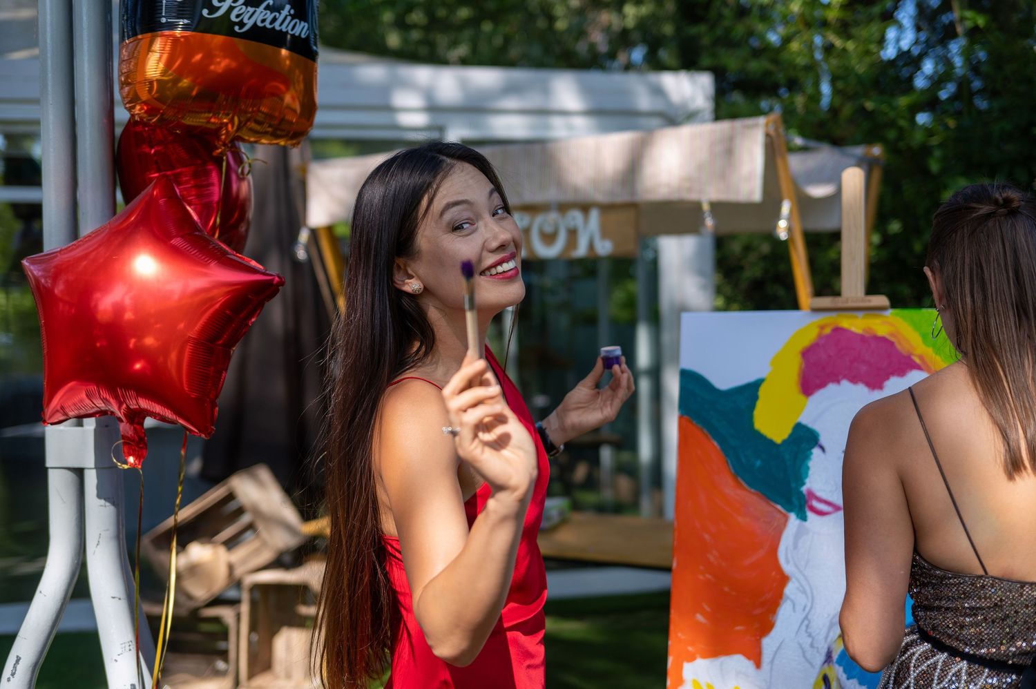 Young people celebrating outdoors with red star balloon and festive decorations.