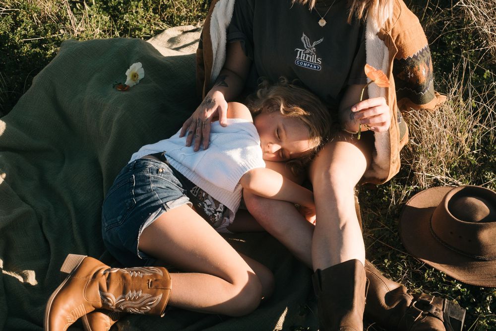 Person relaxing on picnic blanket with boots and ceramics visible.