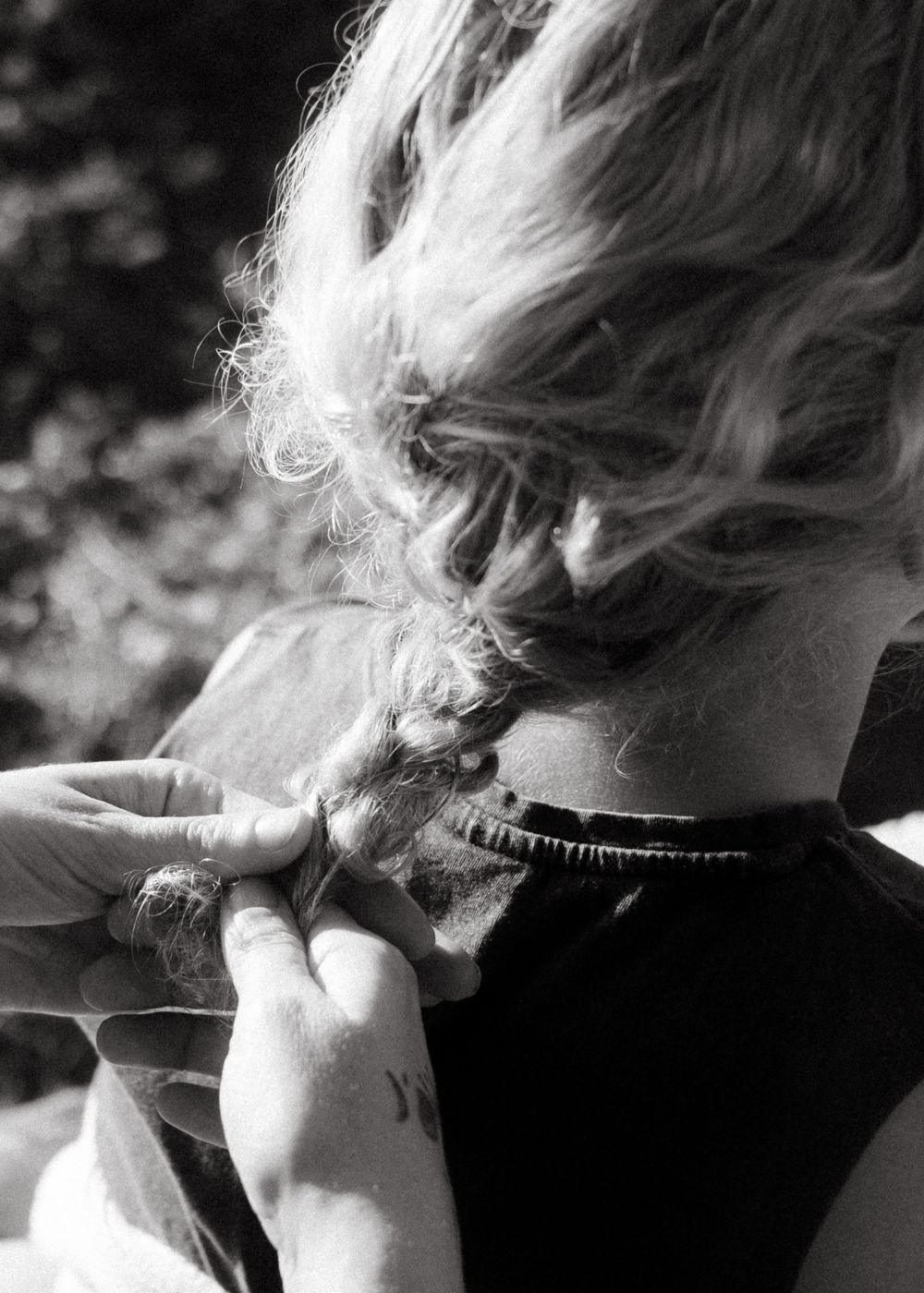 Black and white close-up of hands braiding hair.