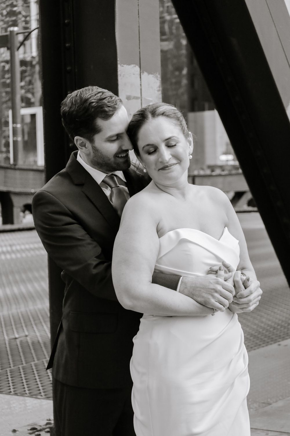 A romantic black and white wedding photo showing a tender moment between a couple on a city street.