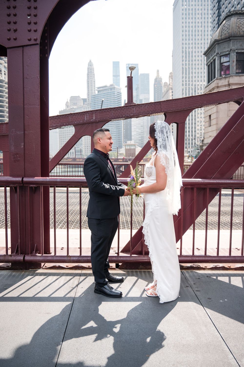 A wedding couple shares a moment on a Chicago bridge with the city skyline visible in the background.