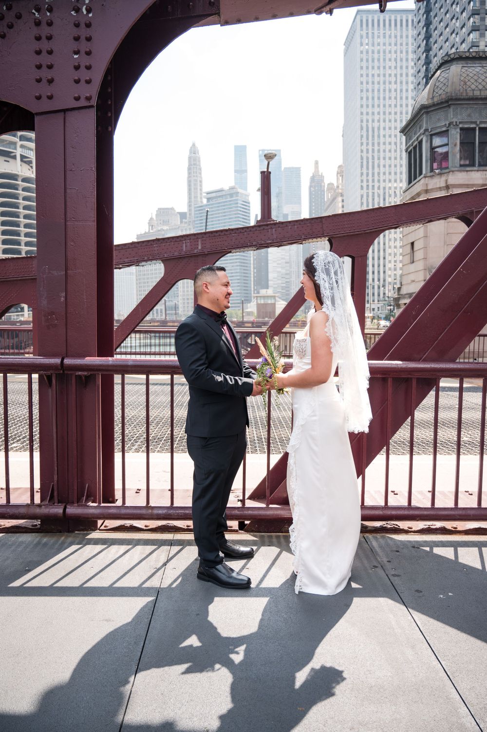 A couple shares a wedding moment on a Chicago bridge with the city skyline visible in the background.