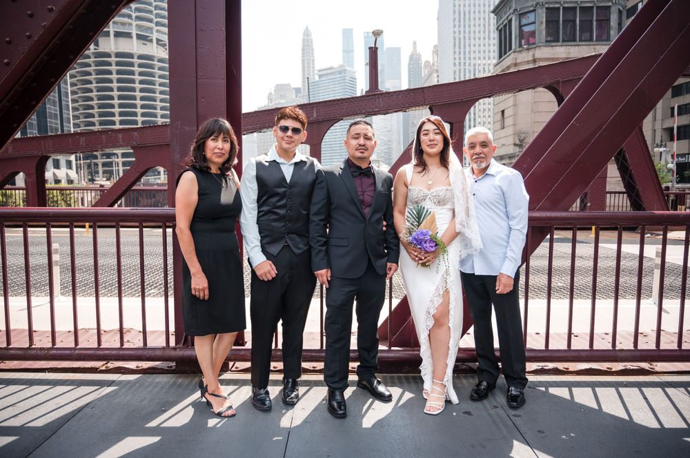 Group of people standing together on a Chicago bridge with downtown skyscrapers visible in the background.