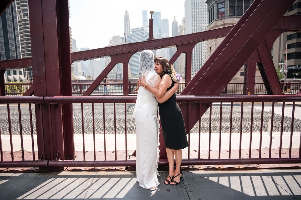 Two people share a romantic moment on Chicago's iconic red steel bridge with the city skyline in the background.