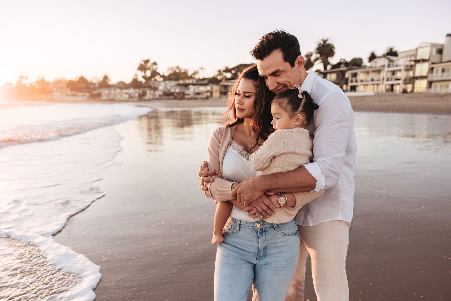 Sweet moment between parent and child at sunset at Miramar Beach in Montecito with golden light creating a warm ambiance.