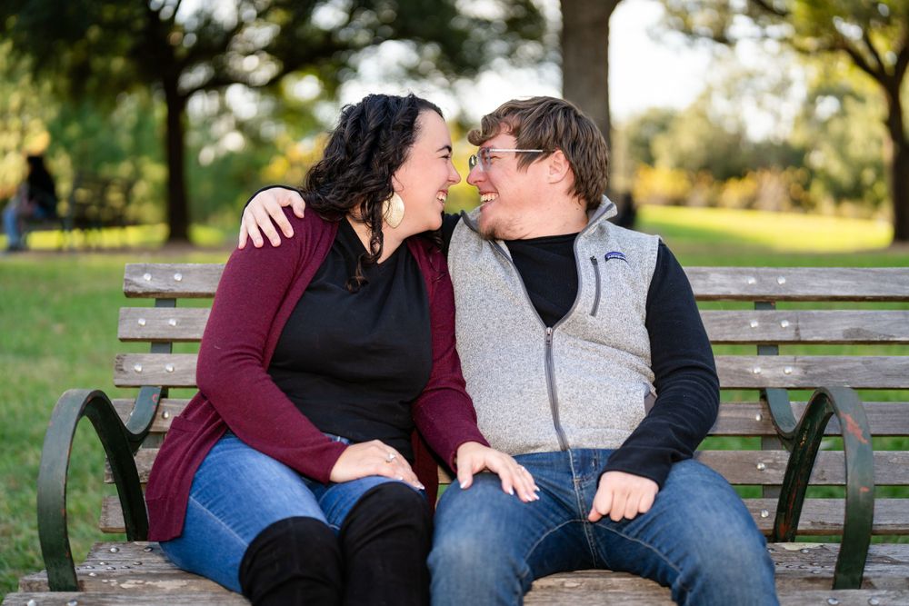 Couple sharing an intimate moment while sitting on a park bench surrounded by greenery.