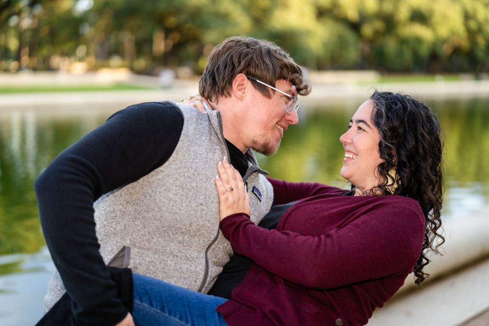 Couple laughing together during romantic outdoor photoshoot by a lake.