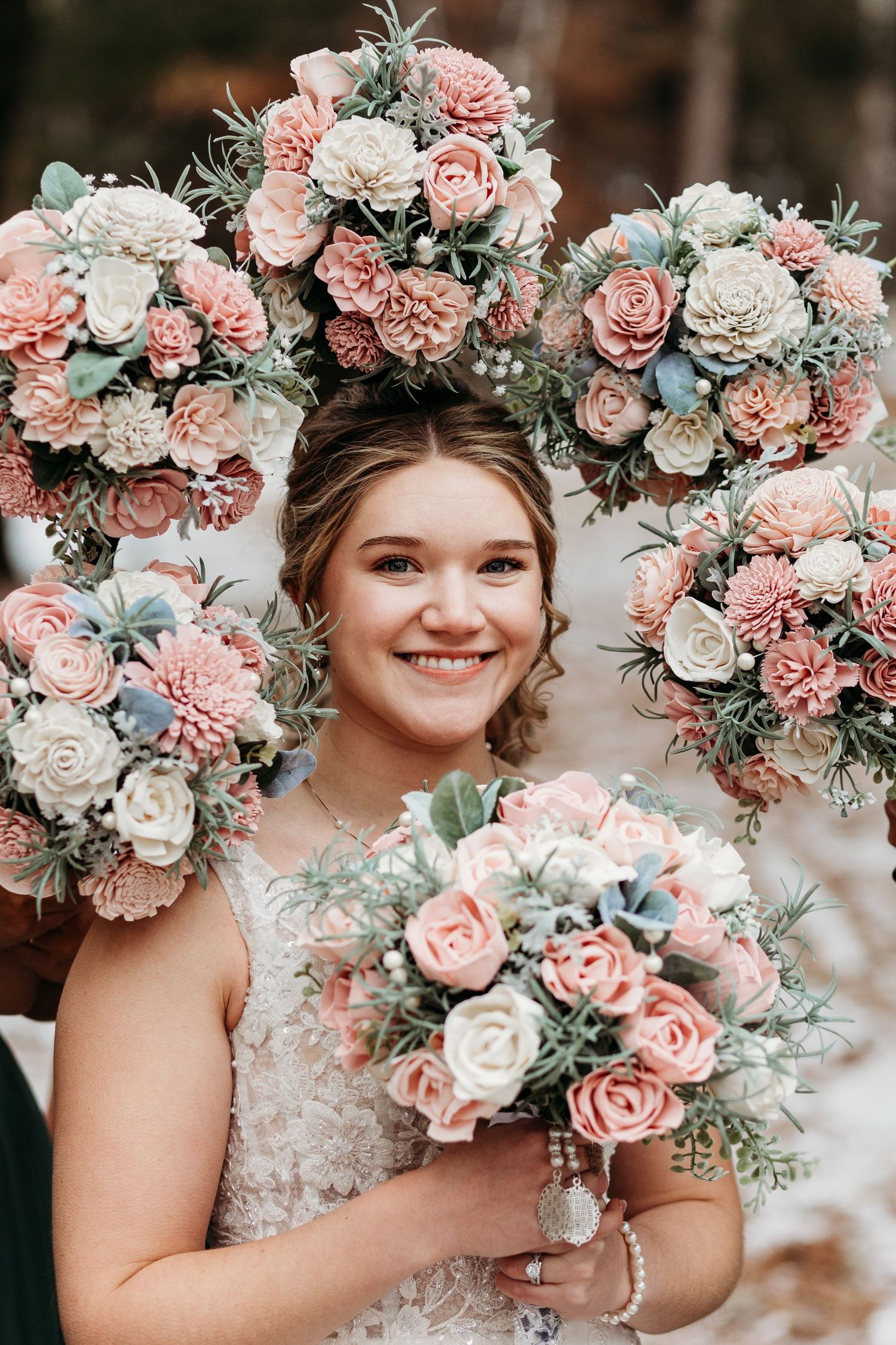 Elegant bridal bouquets in soft pink and white roses with dusty blue accents create a romantic floral arrangement.