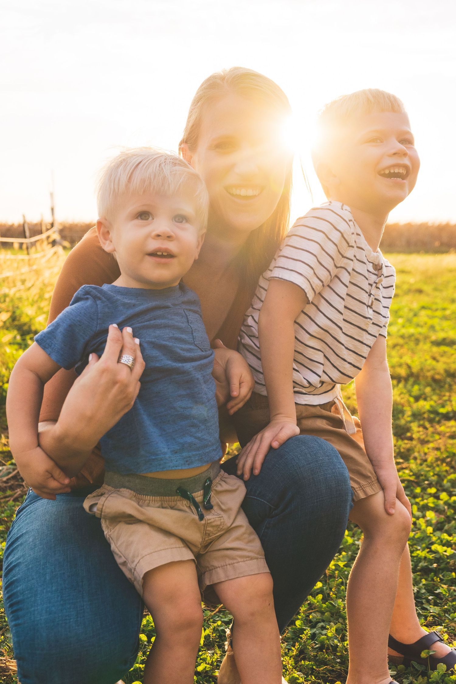 Joyful outdoor portrait of a family enjoying golden hour sunlight together in a grassy field.