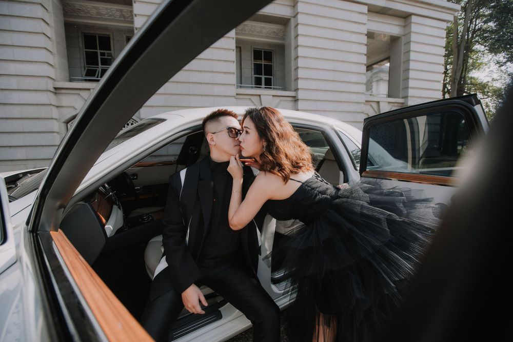 A couple in formal attire shares a romantic moment inside a luxury car with tan leather interior.