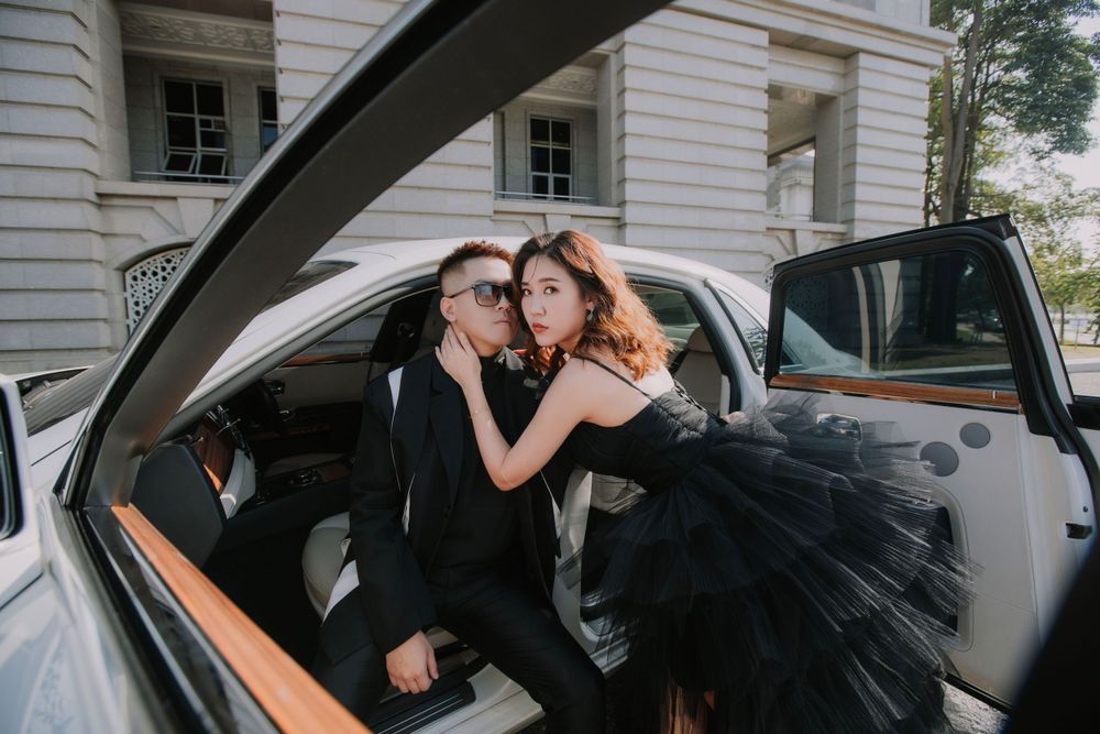 A couple share an intimate moment inside a luxury car wearing elegant black formal wear.