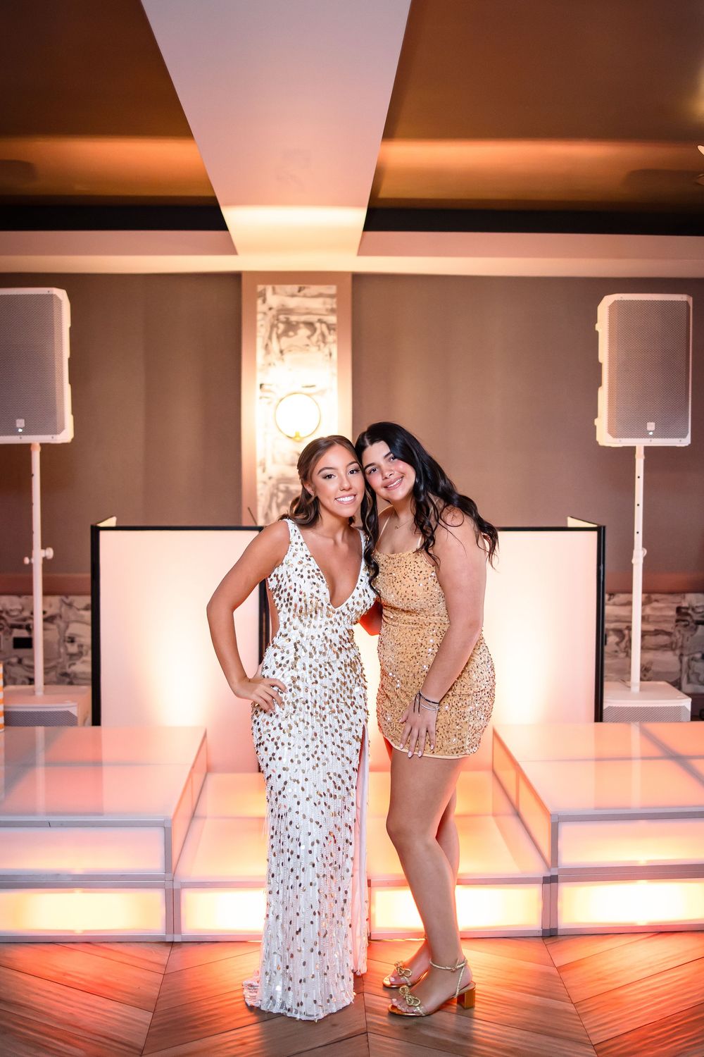 Two dancers practicing in a dance studio with warm lighting and wooden floors.