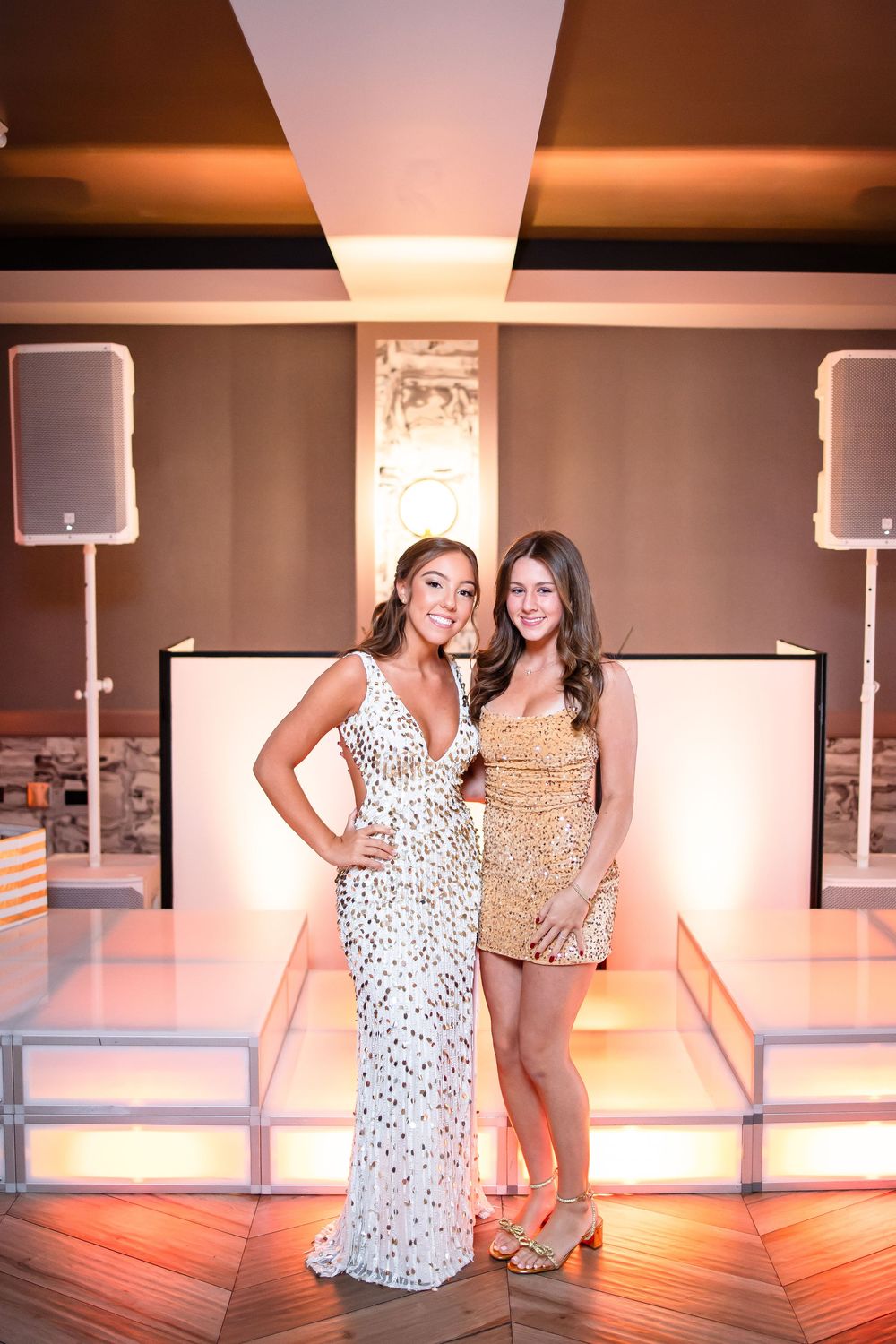 Two people pose together in a dance studio with warm lighting and mirrored walls.