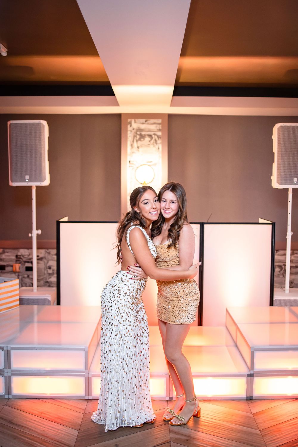 Two people share a candid moment in a dance studio with mirrored walls and warm lighting.
