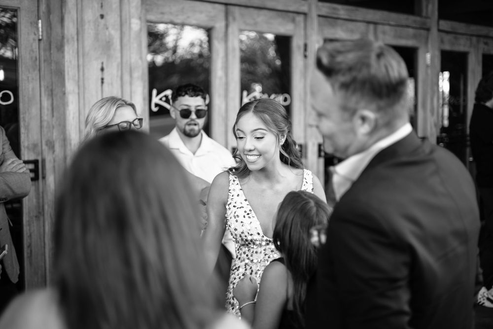 A black and white photograph of guests mingling at a formal event in a rustic venue.
