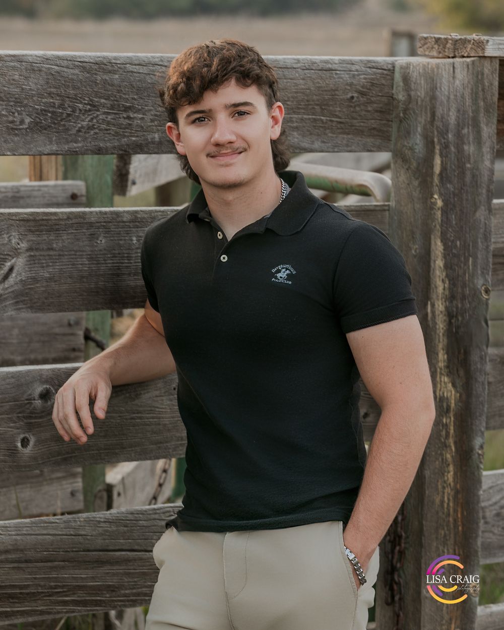 Casual outdoor portrait against a wooden fence in natural lighting.